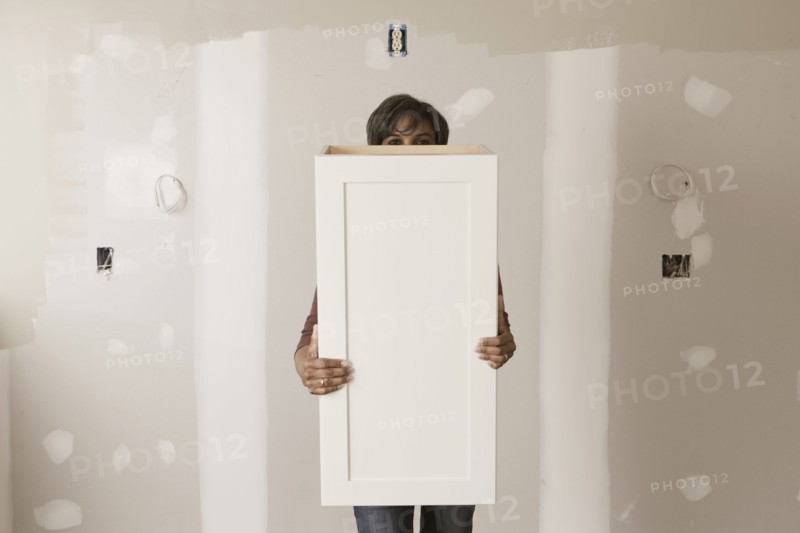 Mixed race woman holding cabinet door in unfinished room
