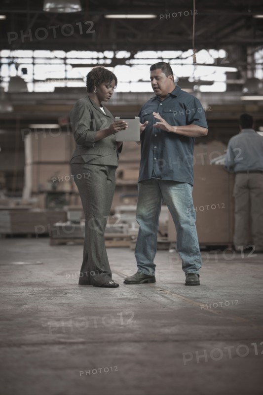 Businesswoman talking to worker in warehouse