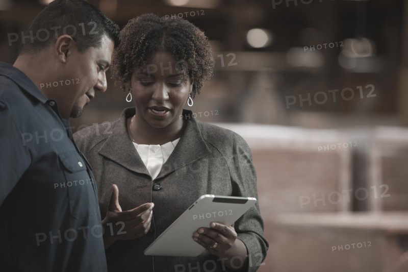 Businesswoman talking to worker in warehouse