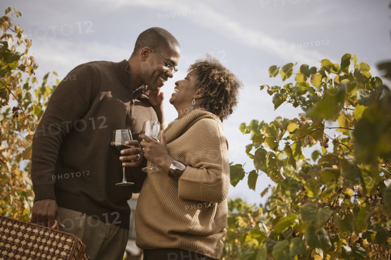 Black couple drinking wine in vineyard