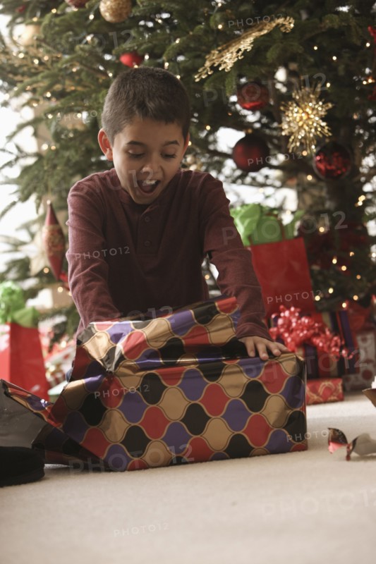 Hispanic boy opening gifts Christmas morning