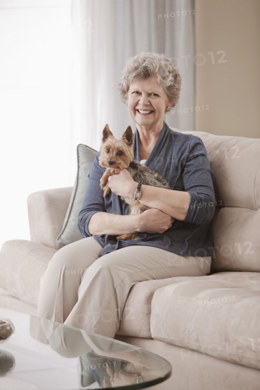 Caucasian woman sitting on sofa holding dog