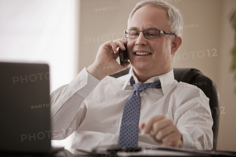 Caucasian businessman talking on cell phone at desk