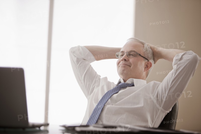 Caucasian businessman sitting at desk with hands on head