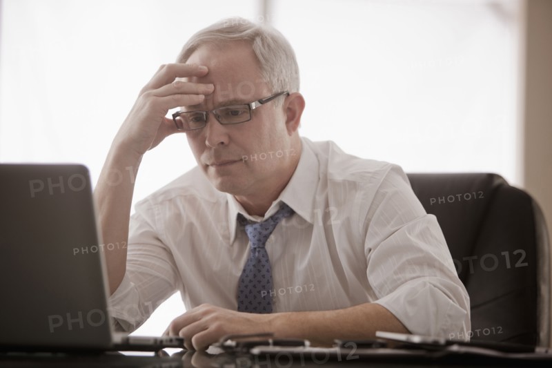 Frustrated Caucasian businessman using laptop at desk
