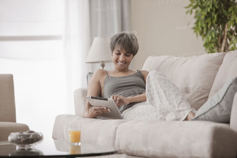 Mixed race woman on sofa using digital tablet