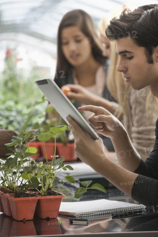 Students working in greenhouse with digital tablet