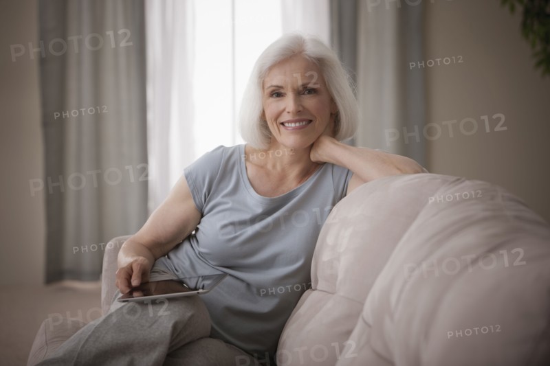 Caucasian woman sitting on sofa with digital tablet