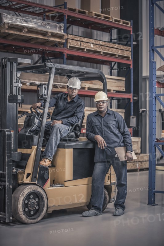 African American workers with forklift in factory