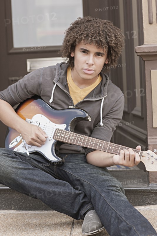 Mixed race teenager playing electric guitar