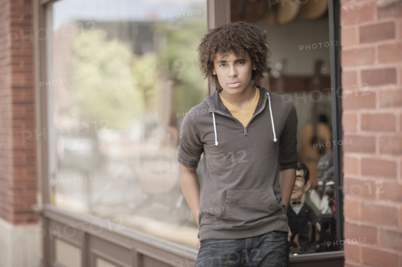 Mixed race teenager standing outside music store