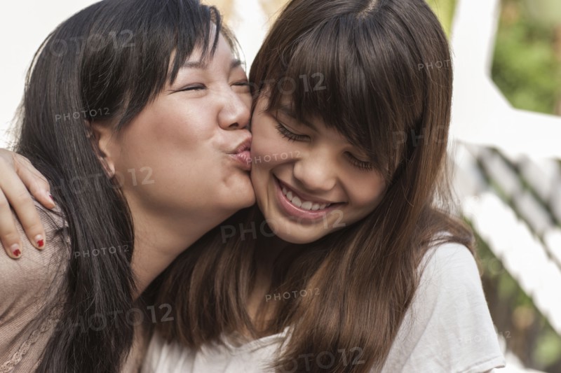 Mother kissing smiling daughter