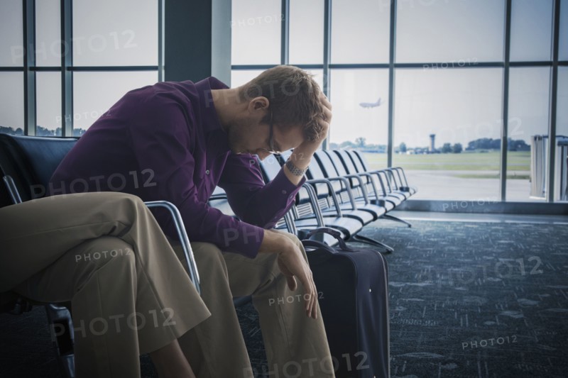 Frustrated Caucasian man sitting airport