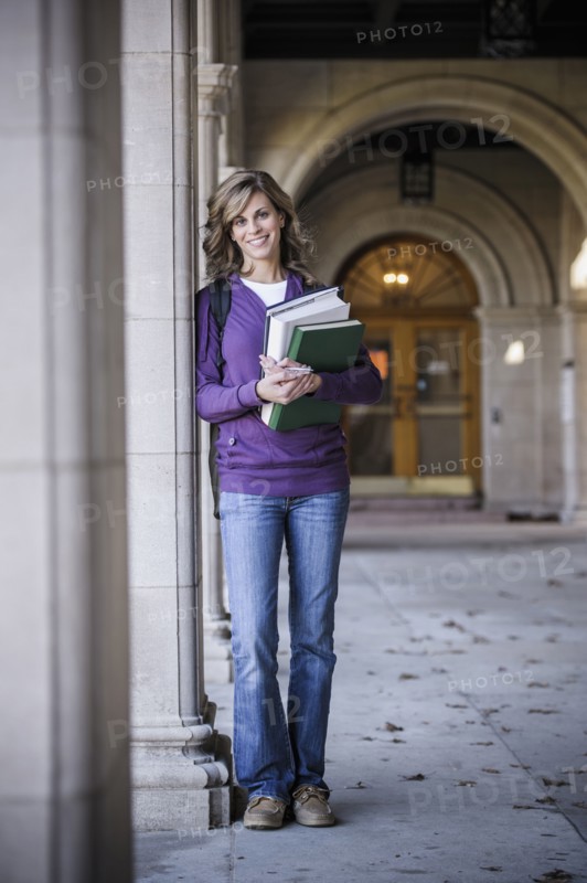 Caucasian student carrying books on campus