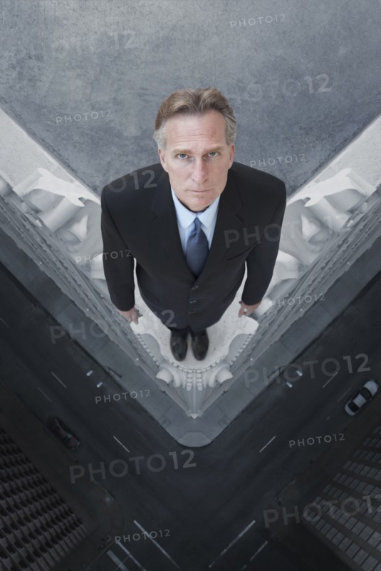 Caucasian businessman on skyscraper ledge