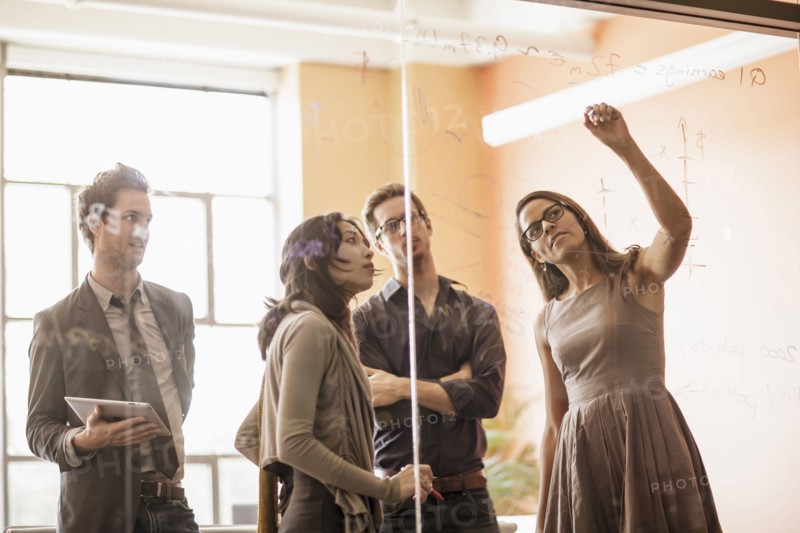 Business people writing on glass wall