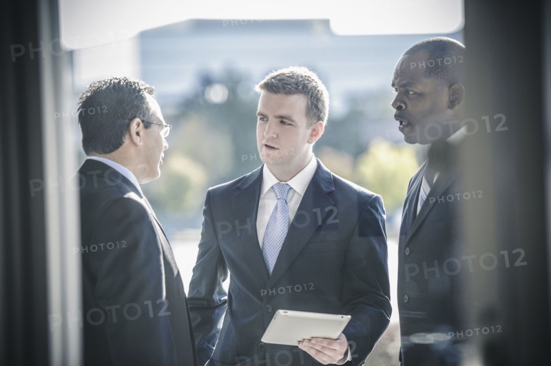 Businessmen using digital tablet outside office