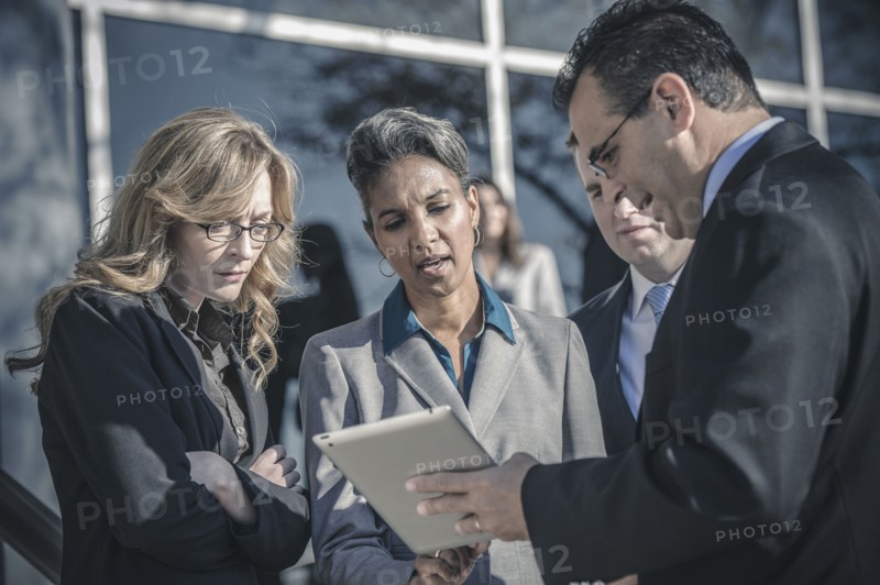 Business people using digital tablet outside office
