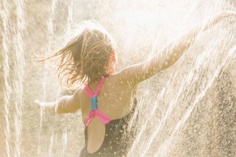 Girl standing in sprinkler
