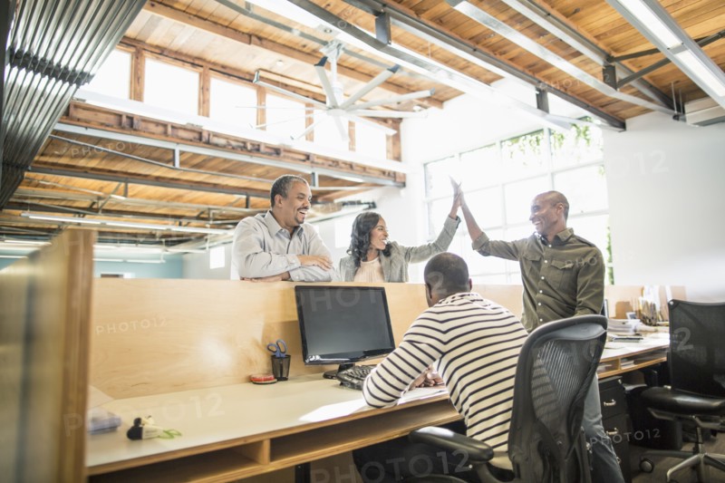 Business people celebrating at desk in office