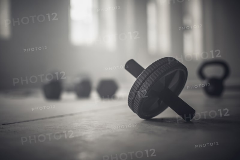 Close up of barbell weights on floor of dark gym
