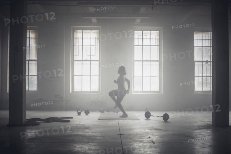 Black woman exercising in dark gym