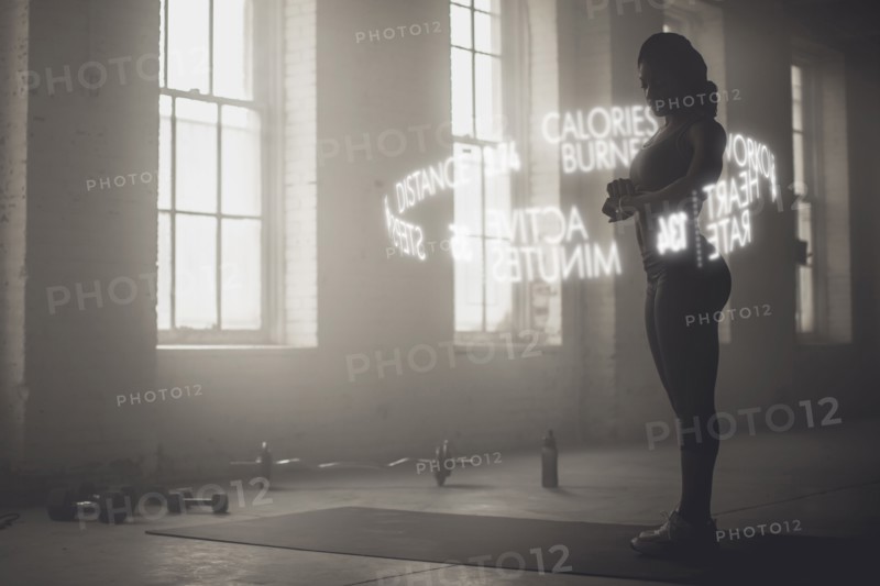 Virtual words circling Black athlete checking fitness tracker