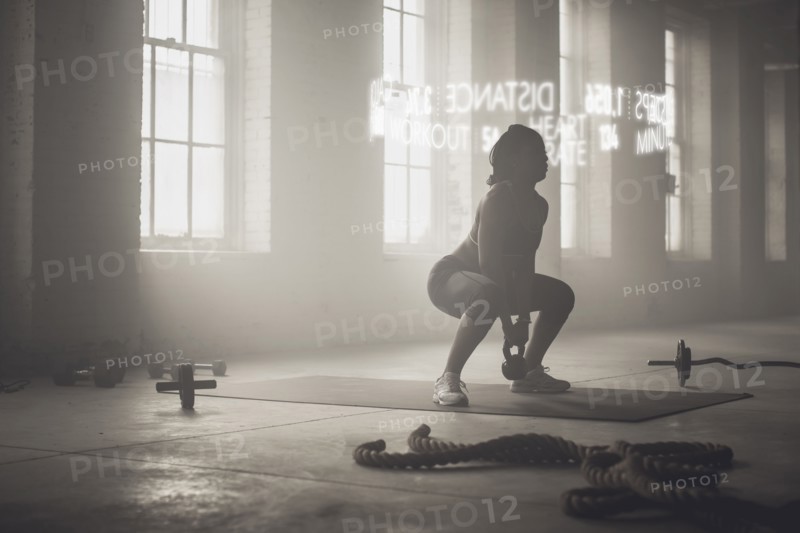 Virtual words circling Black athlete lifting kettlebell