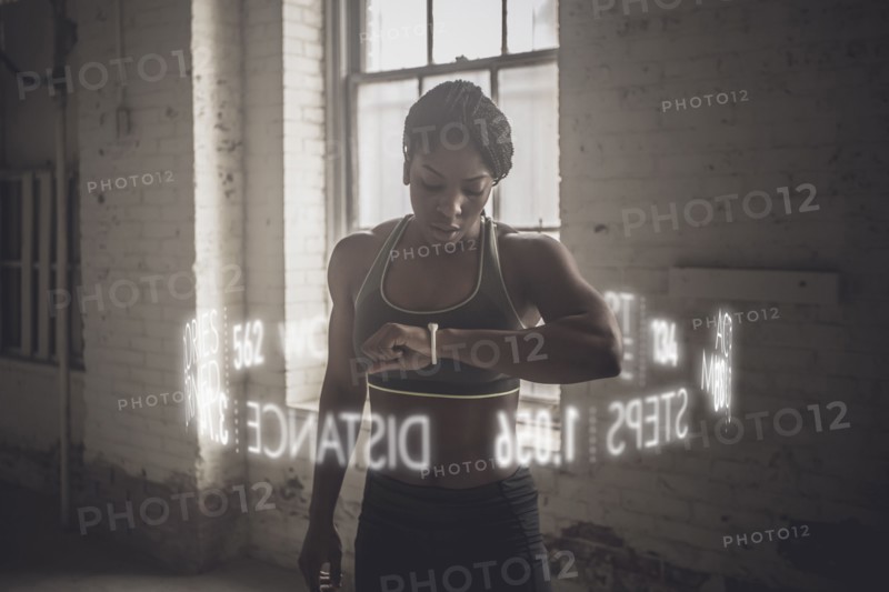 Virtual words circling Black athlete checking fitness tracker