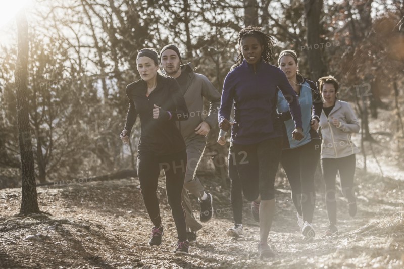 Runners jogging on dirt path in forest