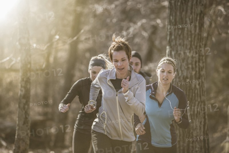 Runners jogging on dirt path in forest