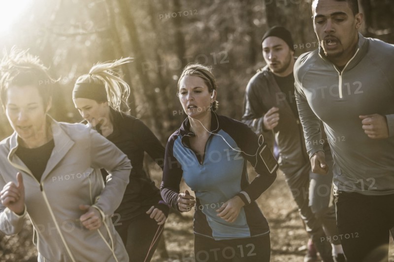 Runners jogging on dirt path in forest
