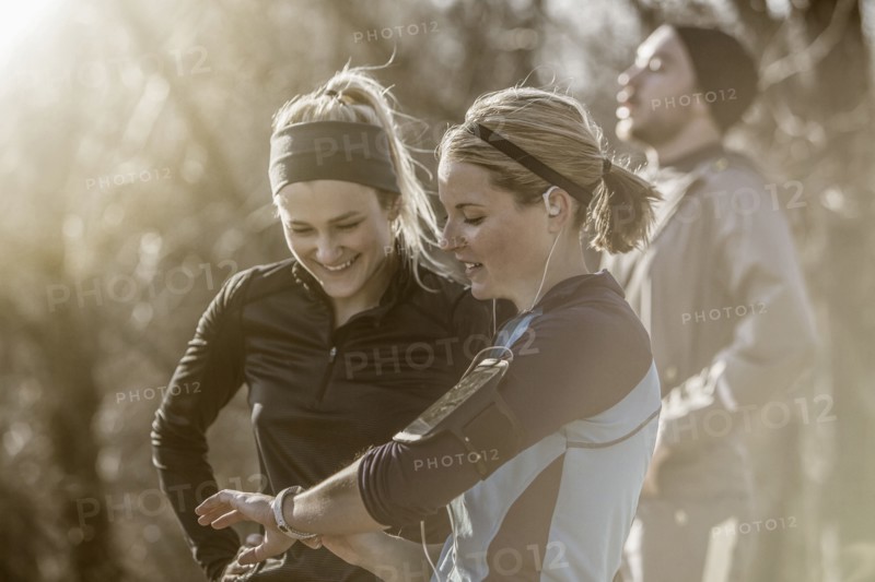 Caucasian runners checking fitness watch in forest