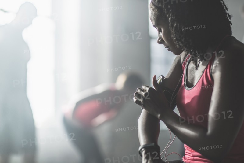 Athlete adjusting mp3 player armband in gym
