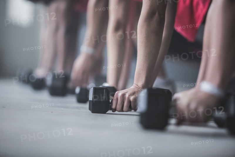 Athletes doing push-ups and lifting weights on floor