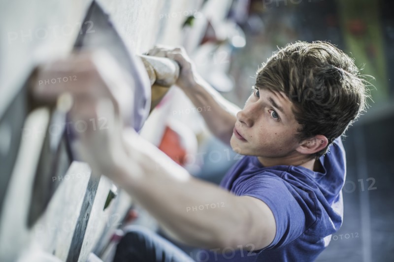Athlete climbing rock wall in gym