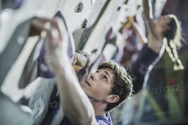 Athletes climbing rock wall in gym