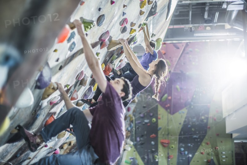 Athletes climbing rock wall in gym