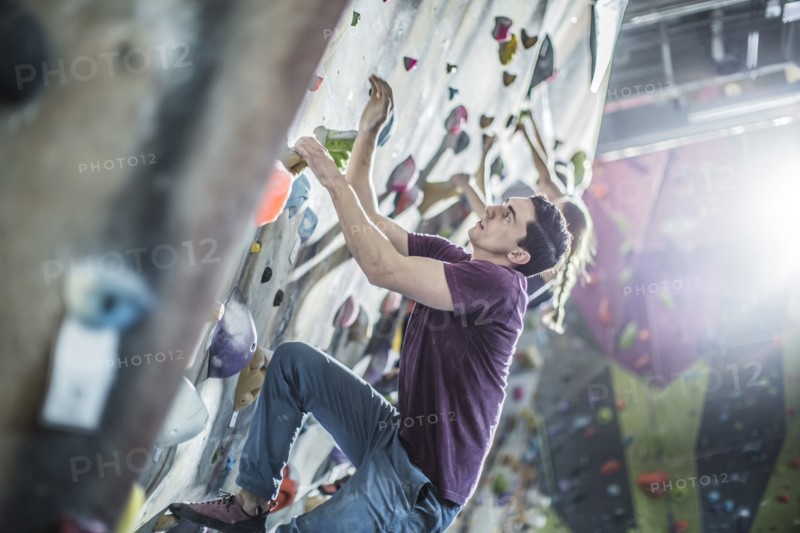Athletes climbing rock wall in gym
