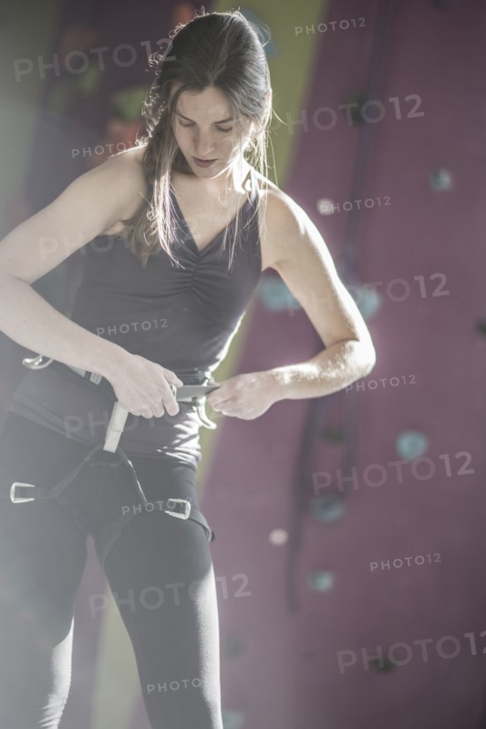 Athlete fastening climbing harness in gym