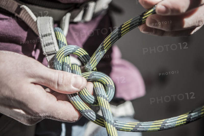 Athlete tying knot on climbing harness