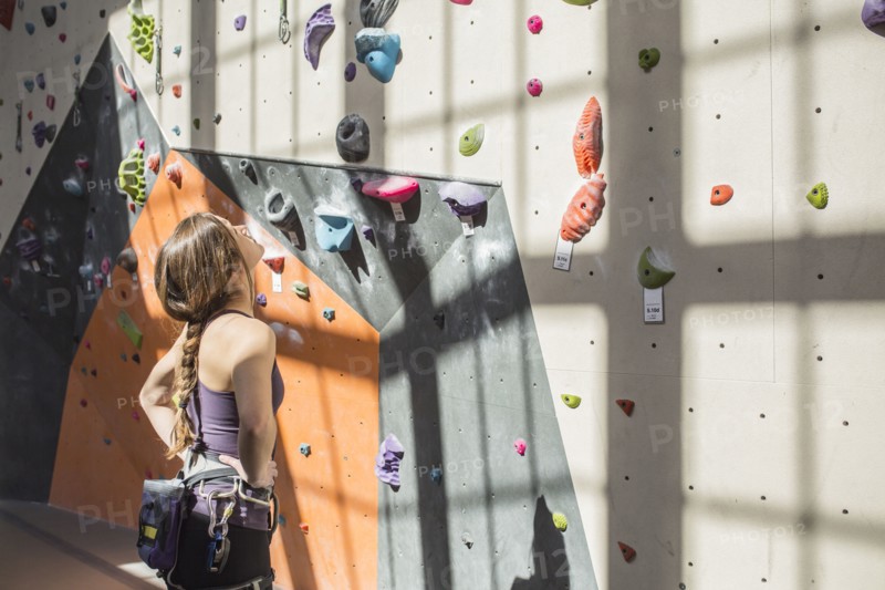Athlete examining rock wall in gym
