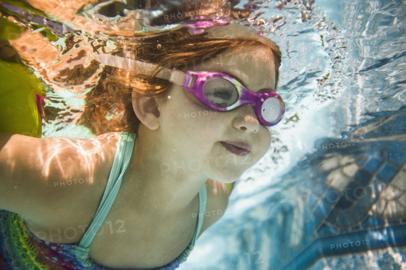 Caucasian girl swimming underwater in swimming pool