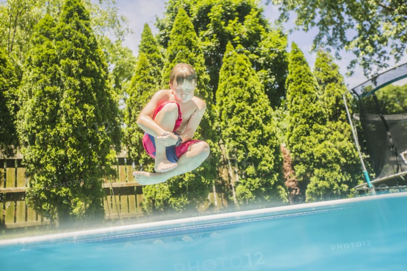 Caucasian boy jumping into swimming pool