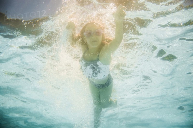Caucasian girl swimming underwater in swimming pool
