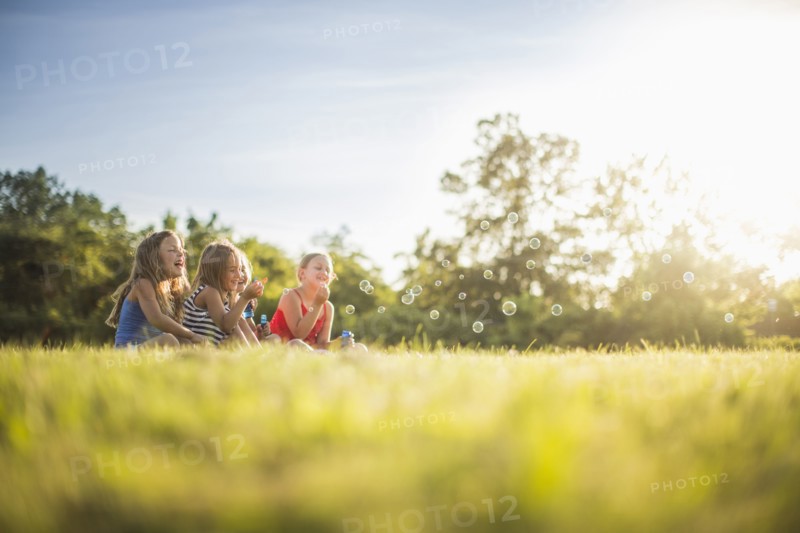 Girls blowing bubbles in grass field