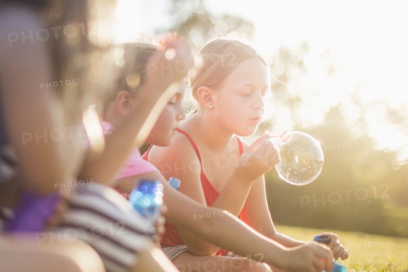 Girls blowing bubbles in grass field
