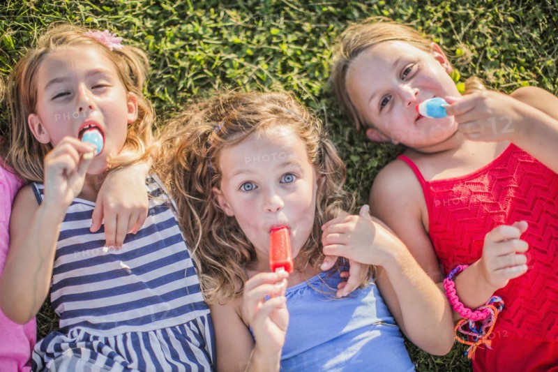 Girls eating flavored ice in grass
