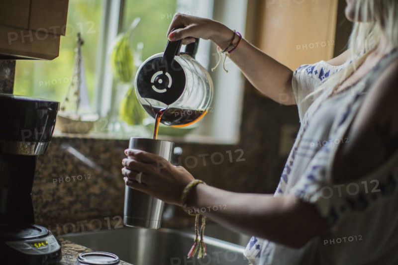 Caucasian woman pouring cup of coffee in kitchen