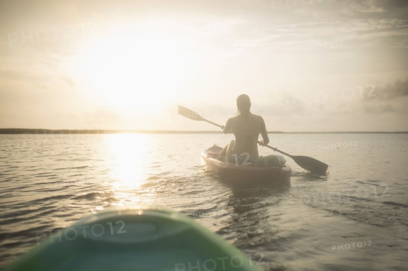 Caucasian woman rowing canoe on still lake